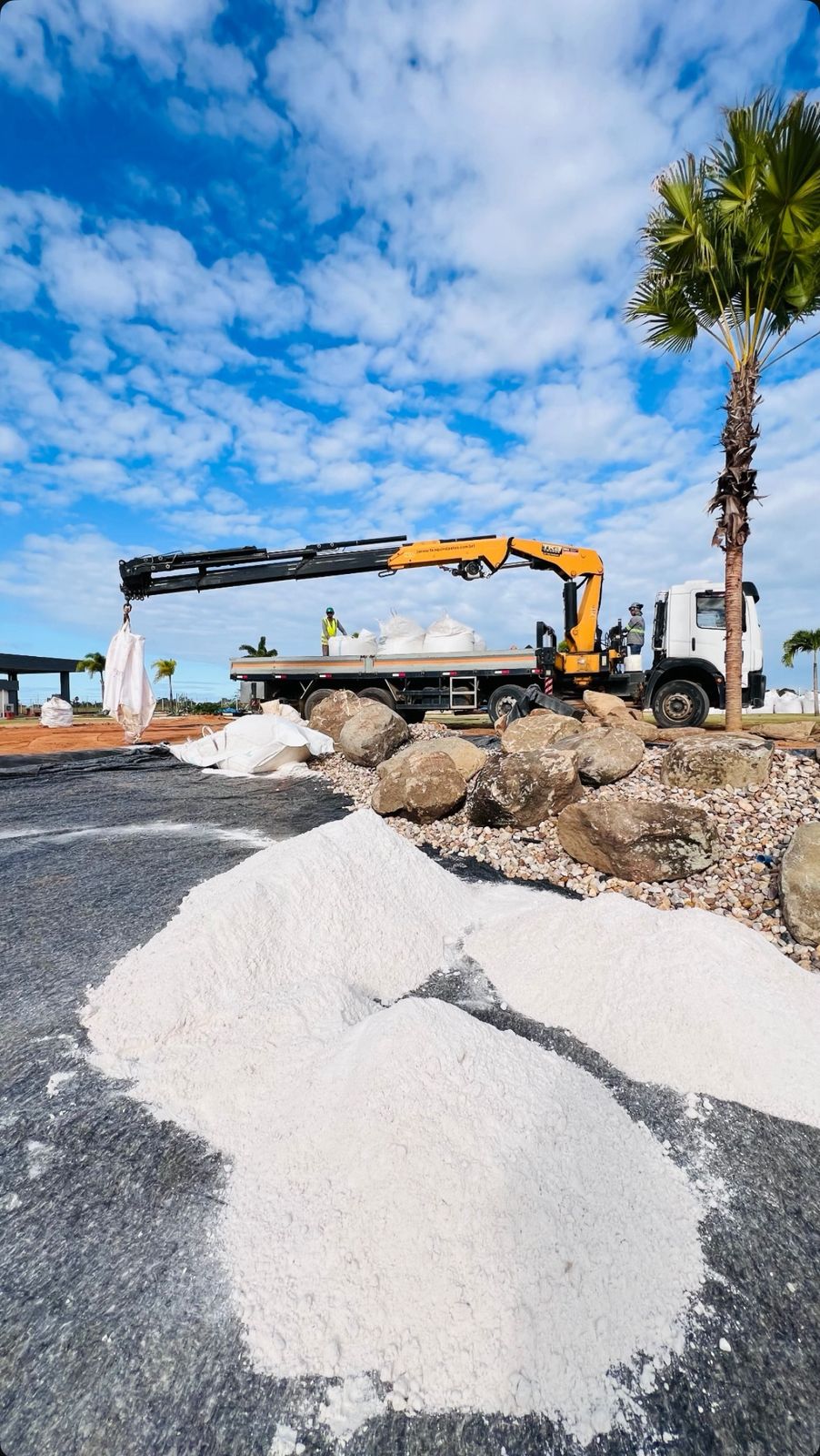 Caminhão com guindaste realizando descarga de big bags de areia
